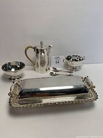 Photo of the rectangular covered dish, pitcher, small bowl, two-handled bowl, and two spoons arranged together.