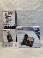 Three Vtech telephones in their original boxes. Two cordless phones and one corded phone with caller ID and speakerphone.