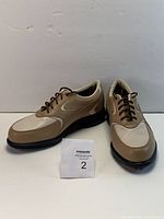 Pair of Oakley women's golf shoes side view showing beige and brown upper with brown laces.