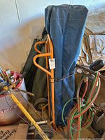 Blue canopy tent bag with orange hand truck behind, showing tent packed and ready for transport.