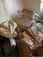 Stacked folded canvas and tarp-like canopy tent materials in beige and brown colors.