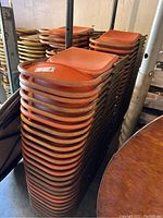 Stacked orange folding chairs with visible dirt and rust on metal frames.