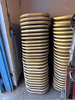 Stacked beige plastic folding chairs with metal legs in storage, showing dirt and wear.