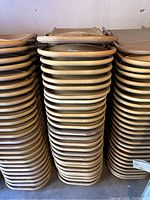 Three stacks of approximately 25 beige textured folding chairs with tubular metal frames, showing signs of use and requiring cleaning.