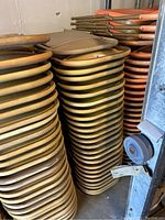 Stack of tan folding chairs with plastic seats and metal frames with signs of rust.
