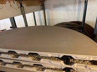 Stack of folded white plastic table tops showing latch mechanisms and edge profile