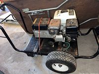 Left side view showing Honda engine, red pull start, black frame, and wheeled dolly.