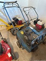 Front perspective view showing blue steel frame, handlebar, mounted gas engine, support wheels