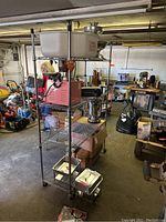 Photo showing metal wire shelving unit on casters with white bin on top, industrial surroundings.