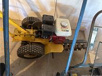 Overall view of the gas-powered chain trencher showing engine, frame, tires, and digging chain.