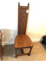 Full view of the carved wooden chair showing tall back with finials and seat.
