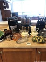 Photo showing the entire kitchen lot on countertop including Keurig maker, spice rack with bottles, cutlery block, and various serving dishes.