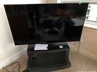 Front of LG flat screen TV on stand with remote and manual on top
