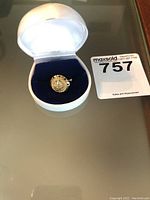 Front view of men's 14k gold ring in white display case on reflective surface with Maxsold lot card visible