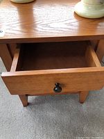 Close-up of the drawer showing black knob and wood grain texture.