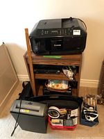 Canon Pixma printer on wooden stand with assorted office supplies around, including a basket of items, a clock, and a calculator, showing overall lot setup.