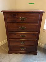 Front view of the pine dresser showing five drawers with brass hardware and the wood grain finish.