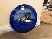 Full view of circular stained glass panel with loon design showing blue tones and overall visual condition