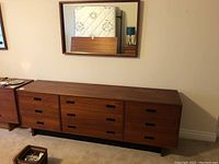 Overall view of teak dresser with mirror mounted above against wall