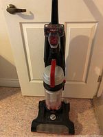 Full view of the Bissell PowerForce Turbo upright vacuum in black with clear dust container and red handle accent.