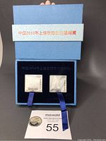 Blue presentation box open showing two hand carved natural shell stamps with Chinese text on the box lining and label
