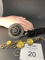 Close-up of the cat eye pendant and the yellow glitter bracelet alongside a quarter for scale.