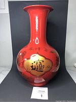 Front view of the large red glazed vase with gold plated patterns under glaze, showing dragon and calligraphy.
