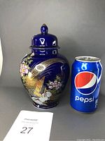 Front view of Japanese samurai jar with lid, showing detailed peacock design next to Pepsi can for size.
