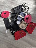 Photo of eleven cosmetic bags of various colors, materials, and sizes spread out on the floor.
