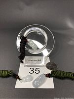 Photo of lot showing three jade pendants each carved with different motifs (monkey, gourd, lotus) placed with rope chains on plate with a coin for scale