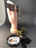 Three metal bangles displayed on and next to a mannequin hand, showing diverse designs and embellishments.