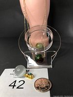 Front view of two gold plated necklaces displayed on a mannequin hand with agate beads pendant and a cat eye gemstone pendant with a coin for scale