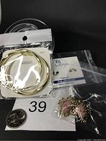 Lot of three pairs of earrings including gold-tone 925 silver hoops, classic cameo earrings, and titanium sleepers shown with a quarter for size reference.