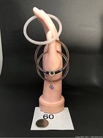 Three small agate bangles displayed on a mannequin hand. One is light pink, two are shades of brown with one having a flower charm with two dangling purple beads.