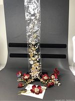 Four bridal hair pins displayed against black background, including red fabric flowers with pearl, crystal, and rhinestone details, one pin in clear packaging