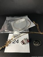Photo showing four jewelry pieces including two necklaces with pendants and two pairs of large round hoop earrings alongside a quarter coin for scale.