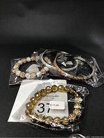 Four-piece lot of Swarovski crystal jewelry including two stretch bracelets and two bangles displayed against black background