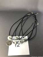 Five Burma jade circular pendant necklaces on black PU leather cords, showing varying shades of jade circular pendants and a US quarter for scale.