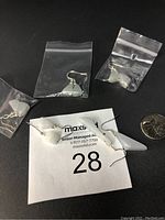 Five pairs of light green to white Burma jade earrings in resealable plastic bags with 925 silver hooks, displayed with a quarter coin for scale.