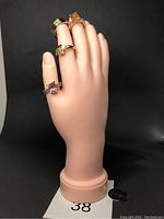 Full view of six rings on mannequin hand showing styles and gemstones.