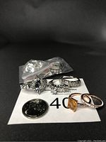Photo showing seven rings with various gemstone cuts including citrine, crystal, and lab created diamond stones. A quarter coin included for size reference.