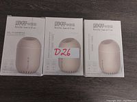 Photo of the front of three humidifier boxes showing the product image as a beige small bottle humidifier.