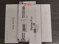 Four white boxes of stylus pens arranged side by side displaying front and side labels, showing branding and product names such as Stylus Pen, Stylus Plus Pen, Active Stylus Pen.