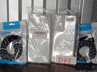 Photo showing two Samsung Galaxy S21 Ultra transparent phone cases in packaging along with two black braided USB-C charging cables also in packaging.