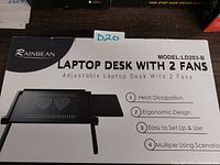 Photo of the Rainbean laptop desk packaging showing model LD203-B, highlighting features including heat dissipation, ergonomic design, multiple usage scenarios, and ease of setup.