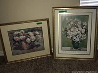 Two framed floral paintings leaning against a wall, showing composition and size relative to each other.