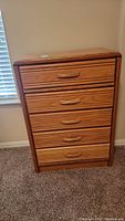 Full view of the Blackhawk chest of drawers with five drawers and wood handles, showing wood grain detail and finish.