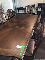 Overview of rectangular wooden dining table surface with two leaves installed and chairs around