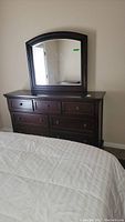 Full front view of dark brown 7-drawer dresser with arched mirror