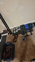 Overview of the hand weights, some dumbbells on floor, ab wheel, push-up bars, and skipping ropes in bin